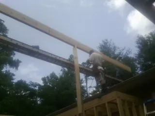 Carpenter setting a ridge beam over a new addition frame — Ice Dam Removal by Roofing Brothers in Glens Falls