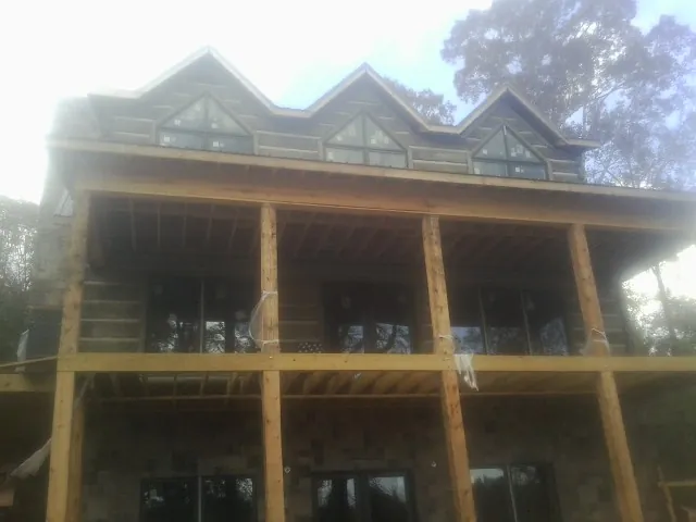 Dormers and porch framing on a large log home under construction — Roof Coating work by our crew in Glens Falls