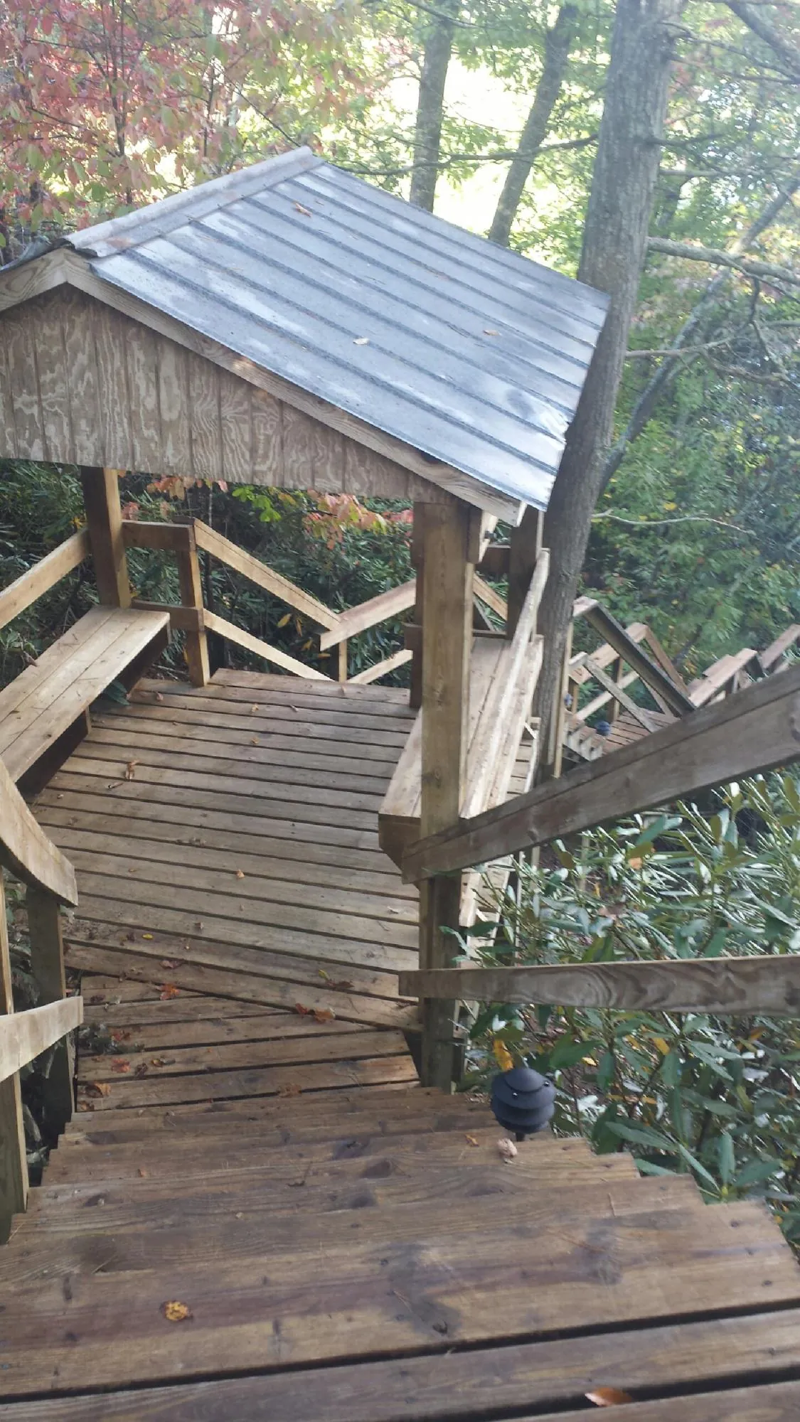 Metal roofed shelter over wooden steps on a wooded walkway — Skylight Repair & Installation work by our crew in Glens Falls