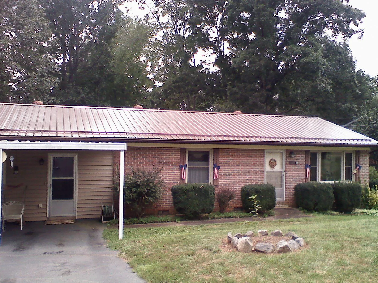 Bronze metal roof and carport on a brick ranch home — Roof Repair work by our crew in Glens Falls