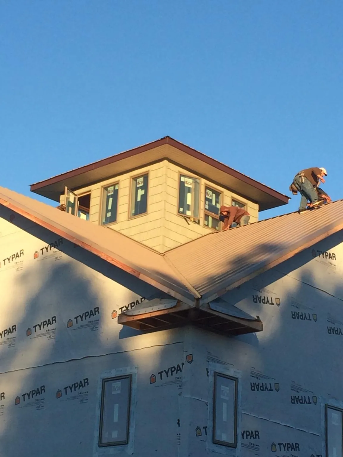 Roofers working around a rooftop cupola on a new metal roof at sunset — Roof Waterproofing in Glens Falls by Roofing Brothers